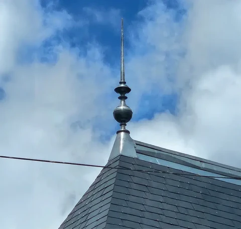 Extérieur, toiture d'ardoise grise avec faîtage métallique surmonté d'un épi de faîtage décoratif