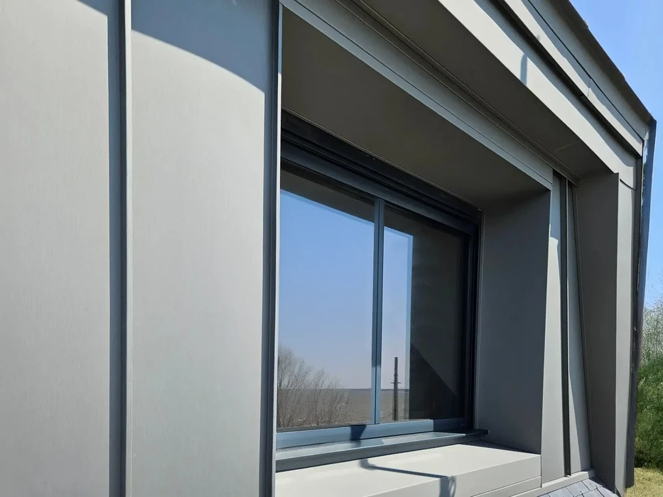 Façade extérieure d'un bâtiment moderne avec baie vitrée coulissante partiellement ouverte