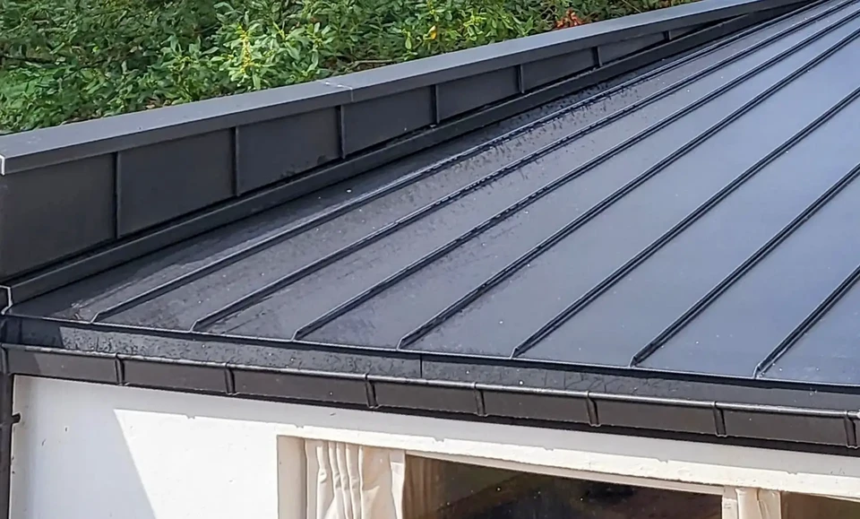 Un ouvrier du constructeur du toit attache une feuille de métal à la cheminée