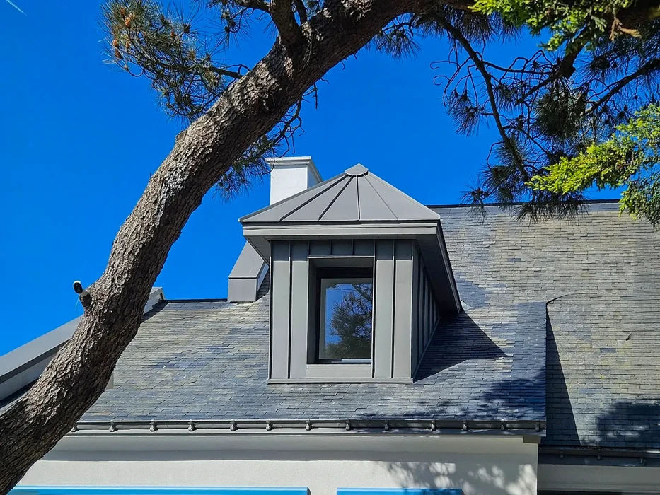 Façade d'immeuble résidentiel avec tour conique à toiture ardoise et finition pierres d'angle