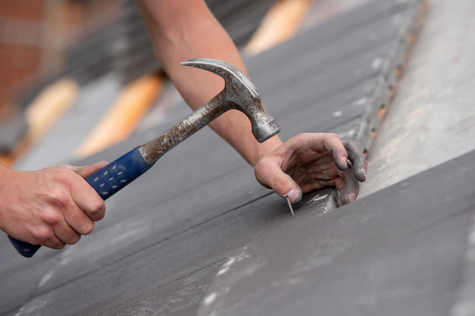 Artisan menuisier souriant dans son atelier de menuiserie, tenant une équerre en bois