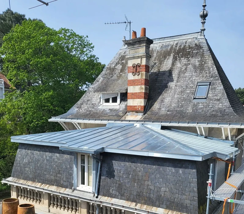 Extérieur d'une maison contemporaine à deux niveaux avec toiture en ardoise grise et lucarnes