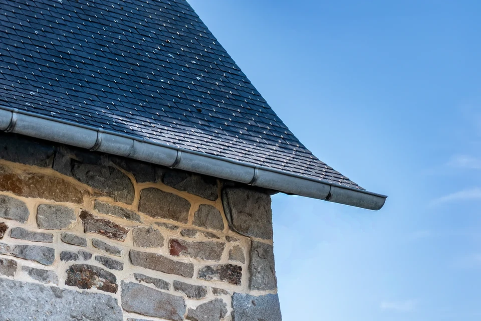 Maison traditionnelle bretonne en pierre de taille avec toiture en ardoise et lucarnes à capucine